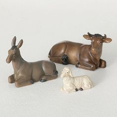 three small figurines of animals laying on the ground next to eachother