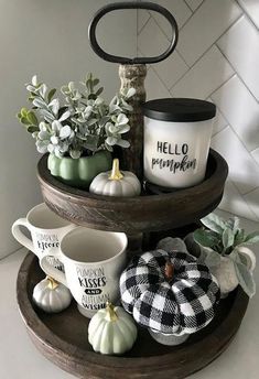 three tiered tray with coffee cups and mugs on it, decorated with black and white pumpkins