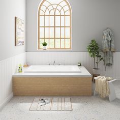 a bathroom with a large bathtub next to a window and rug on the floor