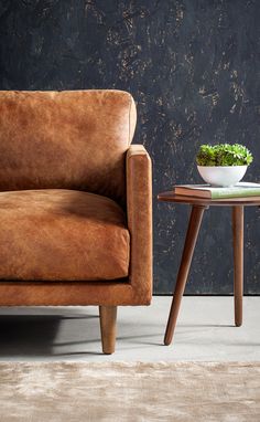 a brown chair sitting next to a small table with a bowl on top of it