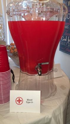 a red drink dispenser sitting on top of a table next to a sign