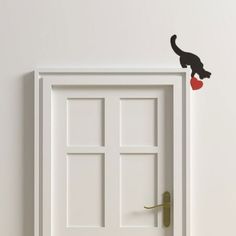 an open door with a black cat on it and a red heart hanging from the handle