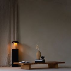 a table with a book, vase and lamp on it