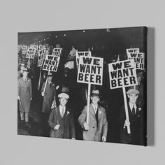 black and white photograph of men holding signs with words we want beer on them in front of a wooden wall