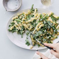 a person is cutting up some food on a plate with a knife and fork next to it