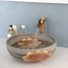 a bathroom sink with a flower design on the bowl and soap dispenser