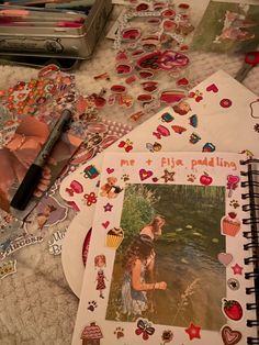 an open notebook with pictures and stickers on the table next to other items that are scattered around