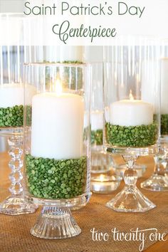 three clear glass vases filled with green beads and white candles sitting on a table