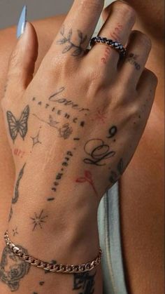 a woman's arm with tattoos on it and a chain around the wrist is shown