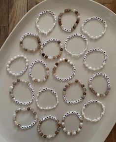 a white plate topped with lots of bracelets on top of a wooden flooring