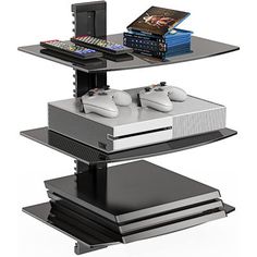 two video game controllers sitting on top of a shelf next to some books and remotes