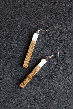 the wooden earrings are hanging from hooks on a black surface with silver earwires