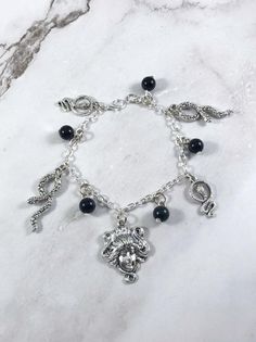 This fun, Medusa themed charm bracelet is the perfect accessory to showcase your love for the Greek myths in a subtle way.Includes 4 snake charms and one Medusa head charm. 5 obsidian beads are in between each charm. Comes in three sizes:Small: 6.5 inches (with extra rings at the end to expand up to 7.5 inches.)Standard: 7.5 inchesLarge: 8.5 inchesSecures with a lobster clasp. Bracelet and charms are made with zinc alloy and beads are natural gemstones. All materials are lead and nickel free. Co Snake Witch, Greek Mythology Jewelry, Mythology Jewelry, Nose Piercing Jewelry, Medusa Head, Witchy Jewelry, Clasp Bracelet, Tourmaline Beads, Greek Myths