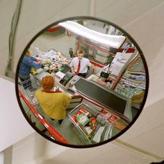 a woman is standing in front of a store looking at her reflection in the mirror