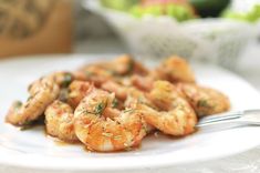 a white plate topped with shrimp next to a bowl of salad