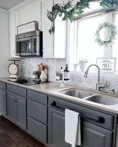 a kitchen with gray cabinets and white counter tops, an oven, dishwasher and sink