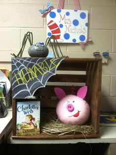 a wooden crate with books and decorations on it, including a pig in a bat costume