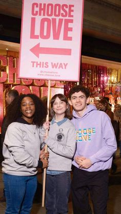 three people standing next to each other holding a sign that says choose love this way