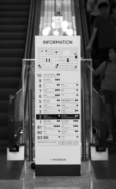 an information sign on the escalator in front of people walking up and down