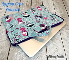 the laptop case is made from fabric and has pink flowers on blue, with purple trim