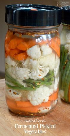 two mason jars filled with carrots, cauliflower and other veggies