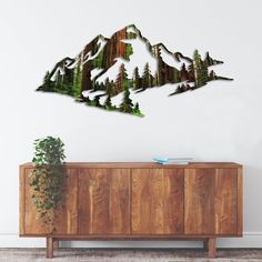 a wooden cabinet sitting next to a wall with a mountain cut out of wood on it