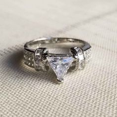 a white gold ring with a princess cut diamond in the center and side stones on each band