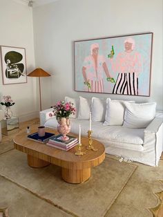 a living room filled with furniture and a painting on the wall above it's coffee table