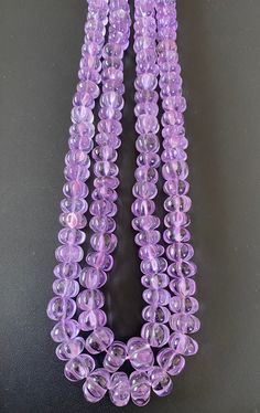 three strands of purple glass beads on a black surface