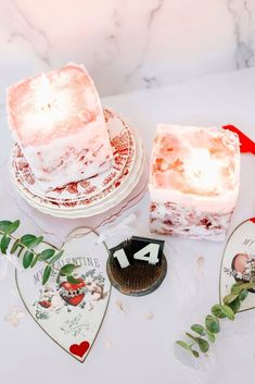 two cakes with frosting on them sitting on a table next to candles and other decorations