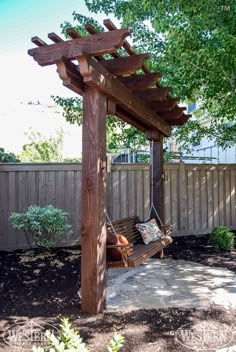 a wooden bench sitting under a tree next to a covered area with a hammock