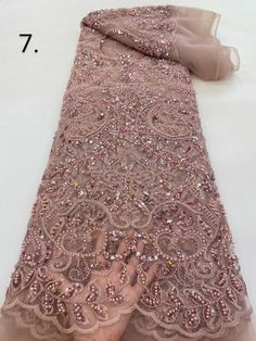 a person is touching the lace on a pink dress that has sequins and beads