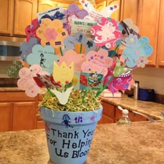 a flower pot filled with lots of paper cutouts and flowers on top of a counter