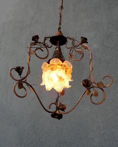 a chandelier hanging from the ceiling with an orange light bulb in it's center