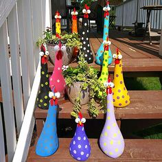 several colorful vases with flowers in them sitting on a wooden porch steps next to potted plants