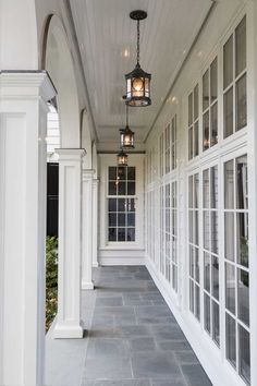 the front porch is lined with windows and white pillars, along with a lantern hanging from the ceiling