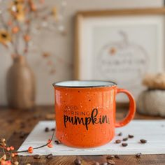 an orange coffee mug with the words good morning pumpkin printed on it sitting on a napkin