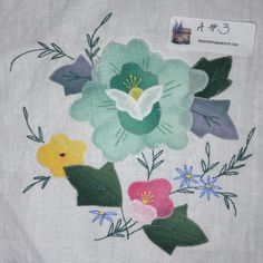 an embroidered piece of cloth with flowers and leaves on the front, in various colors