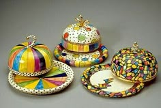 four pieces of colorful pottery on a gray surface with polka dots and circles around them