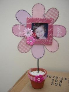 a pink flower is placed next to a potted plant with a photo on it