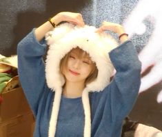 a young woman wearing a blue shirt and white hat with her hands on her head