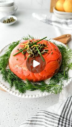 a piece of salmon on a white plate with green garnish and sprouts