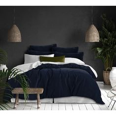 a bedroom with black walls and white flooring is pictured in this image, there are plants on either side of the bed