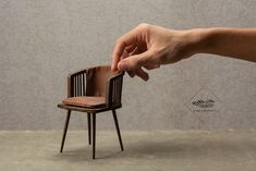 a hand reaching for a miniature chair