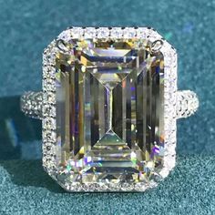 an emerald colored diamond surrounded by white and yellow diamonds on top of a blue surface