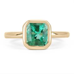 a gold ring with an emerald colored stone in the center and a thin band around it