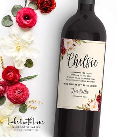 a bottle of wine sitting next to flowers on top of a white table with red and pink roses