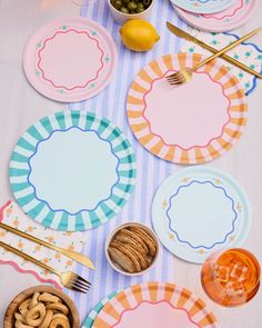 colorful plates and utensils laid out on a striped tablecloth with place settings