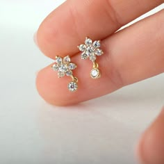 "Small but dazzling, these beautiful stud earrings feature sparkly flower-shaped zirconia gemstones and a tiny bezel-set CZ drop charm. Look gorgeous worn alone to add some sparkle to your ears and also layer beautifully with other dainty earrings for those with multiple piercings. ∙Sold individually (1 earring) or by pair (2 earrings) * D E T A I L S * ∙ Material: .925 Sterling Silver or 18K Gold Plated over .925 Sterling Silver ∙ Stone: White Zirconia ∙ Dimensions: Flower: 7mm // Total height: Small Earrings Gold, Star Dangle Earrings, Gold Earrings Models, Beautiful Stud Earrings, Diamond Earrings Design, Earrings Star, Gold Jewelry Stores, Indian Jewellery Design Earrings, Jewelry Bracelets Gold