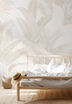 a bed with white sheets and pillows in front of a wallpapered plant pattern